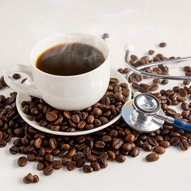 Kaffeetasse mit Bohnen und Stethoskop als Gesundheitsmotiv