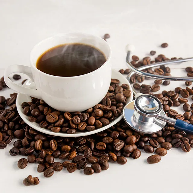 Kaffeetasse mit Bohnen und Stethoskop als Gesundheitsmotiv