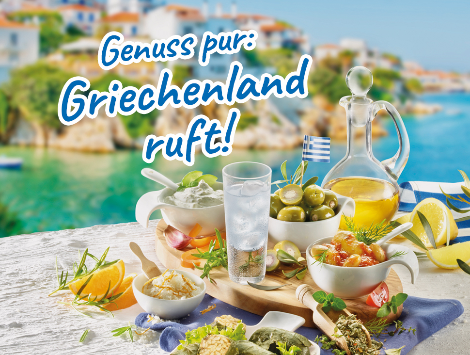 Mediterrane Tafel mit Oliven, Zitronen und Ouzo vor griechischer Küstenkulisse.