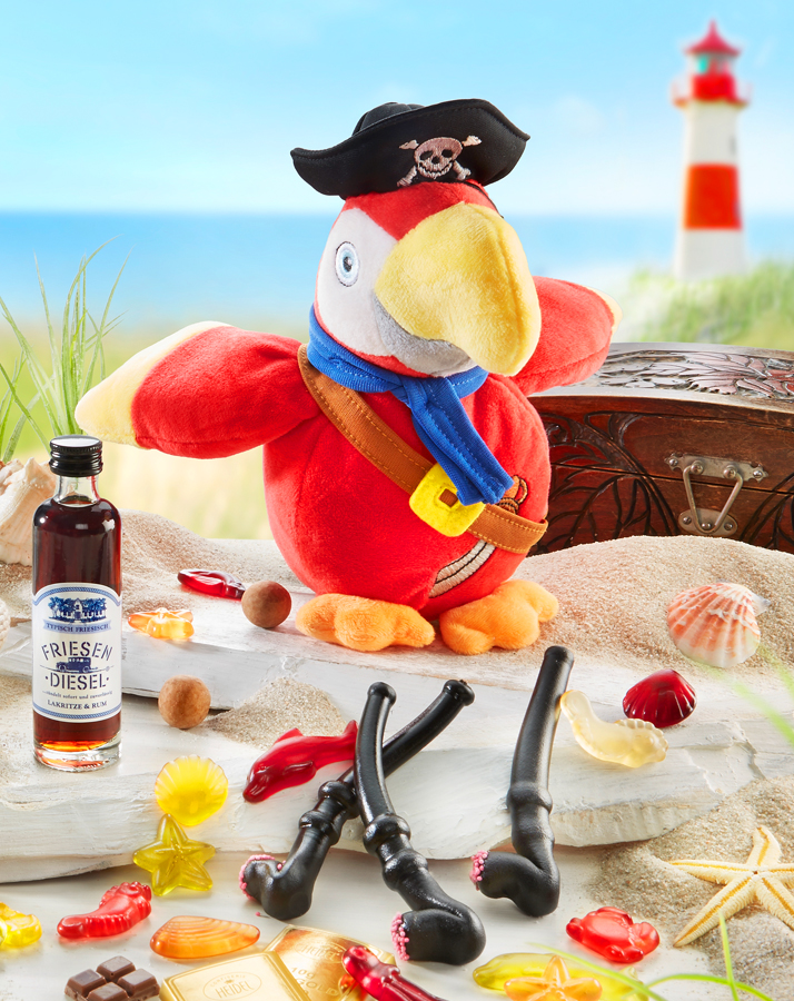 Stoff-Papagei mit Piratenhut und bunten Naschereien am Strand