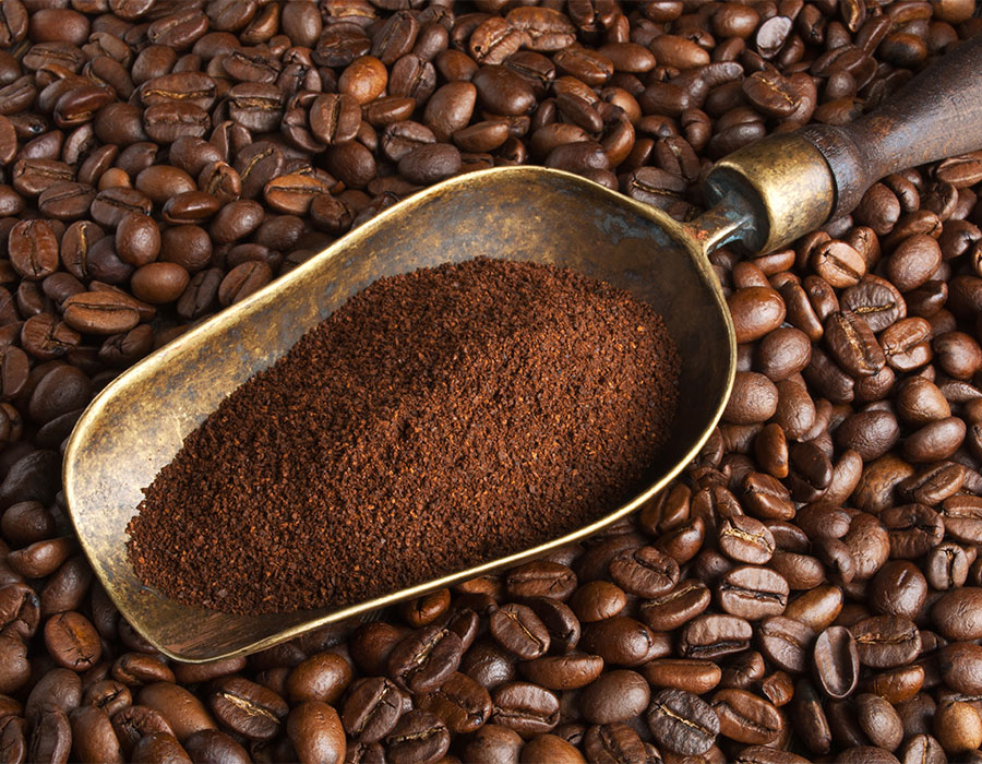 Gemahlener Kaffee in Metallschaufel auf Kaffeebohnen