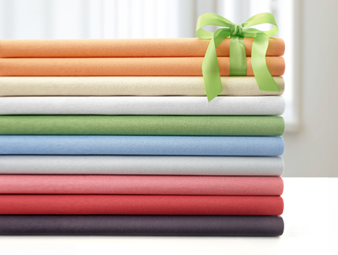 Farbige Spannbettlaken ordentlich gestapelt mit Geschenkband