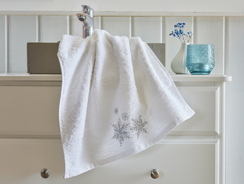 Weißes Handtuch mit Schneeflockenstickerei im winterlichen Bad