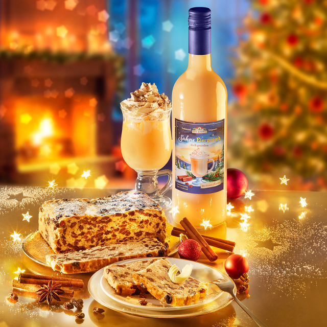 Christstollen mit Sahne-Eierpunsch vor weihnachtlicher Kaminstimmung