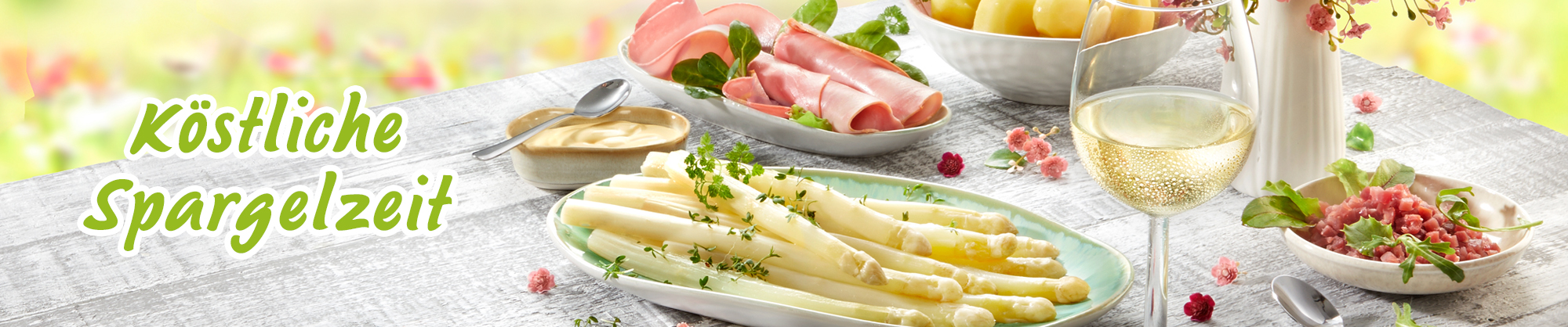 Frischer Spargel mit Schinken, Kartoffeln und Wein auf Frühlingstisch
