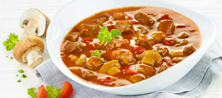 Gulaschsuppe mit Fleisch, Paprika und Pilzen in einer weißen Schale