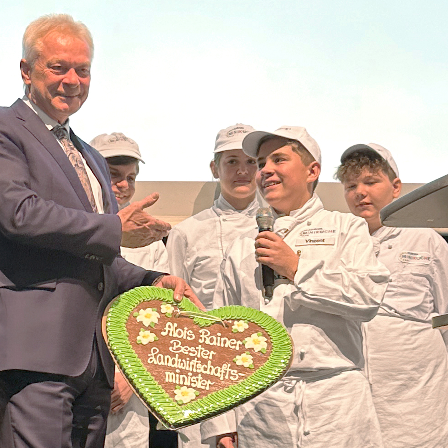 Minikoch überreicht Lebkuchenherz an Politiker auf der Bühne