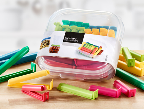 Bunte Verschlussclips in Kunststoffbox auf Holztisch.
