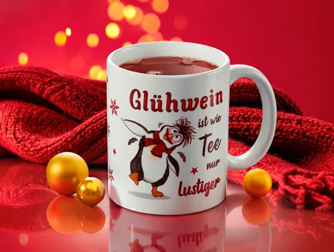 Tasse mit Weihnachtsmotiv und roter Dekoration zur Winterzeit