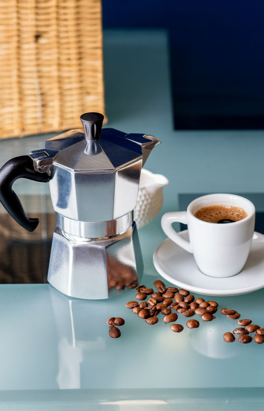 Espressokocher mit Tasse und Kaffeebohnen auf Tisch