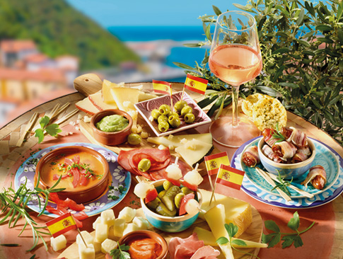 Spanische Tapas mit Oliven, Käse, Chorizo und Wein vor mediterraner Kulisse