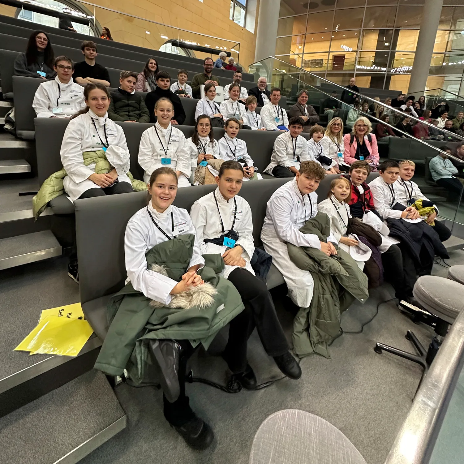 Miniköchinnen und Miniköche sitzen gemeinsam auf der Tribüne im Bundestag