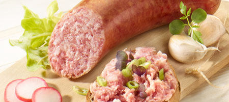Streichmettwurst auf Holzbrett mit Brot, Radieschen und frischen Kräutern