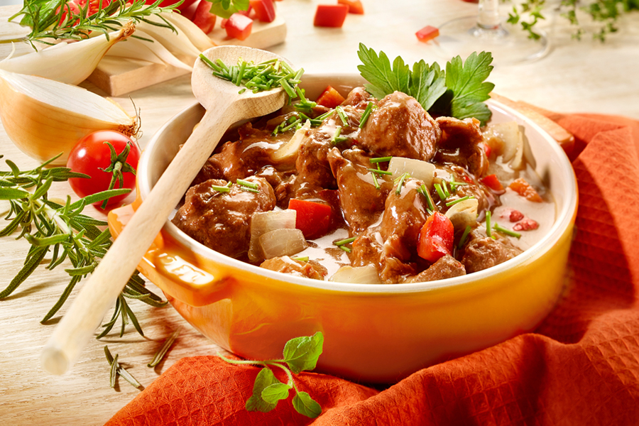 Schmorgericht mit Fleisch, Gemüse und Kräutern in Auflaufform