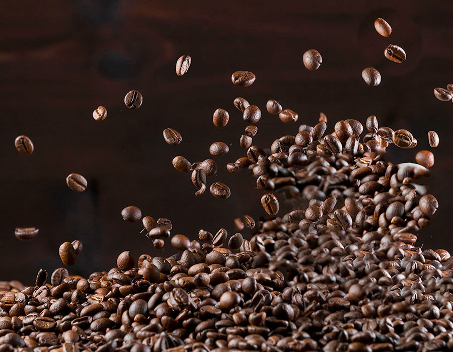 Fallende Kaffeebohnen in Bewegung vor dunklem Hintergrund