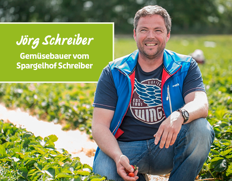 Gemüsebauer sitzt auf dem Feld und lächelt in die Kamera