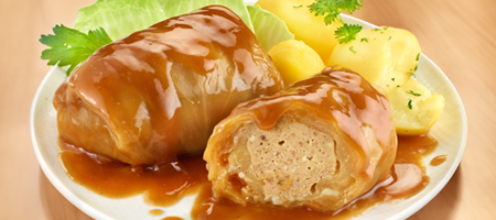 Herzhafte Kohlrouladen mit Bratensoße und Kartoffeln auf einem weißen Teller