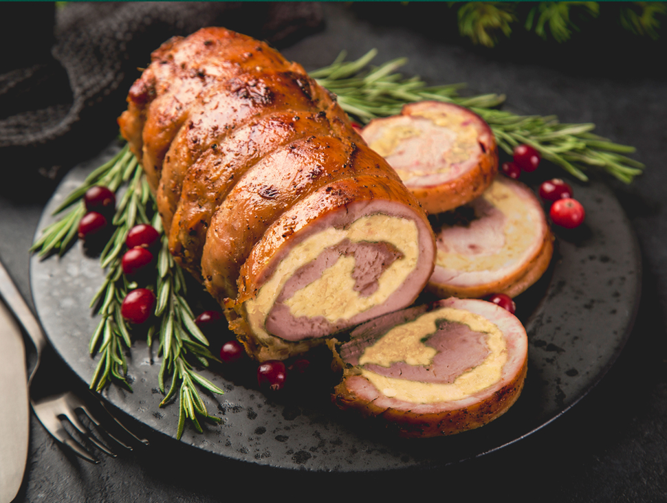 Gefüllter Braten mit Kräutern und Preiselbeeren auf schwarzem Teller