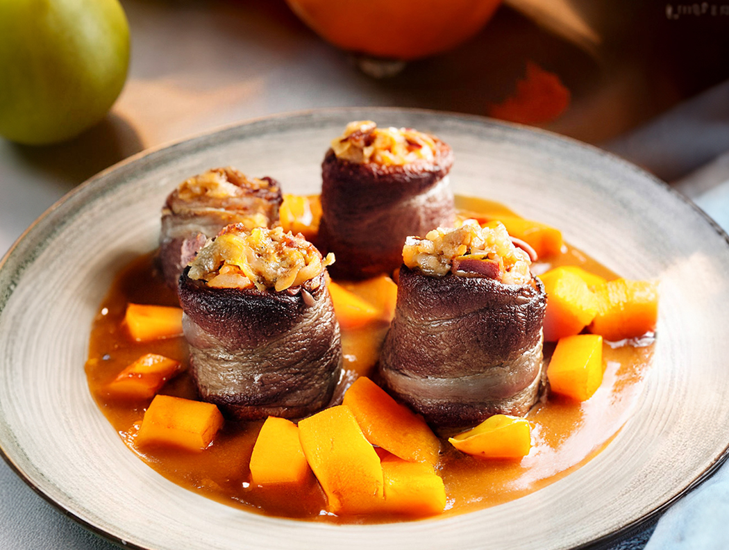 Rinderrouladen mit Speck-Kürbis-Füllung, serviert mit Kürbisstücken und Soße