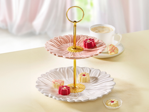 Etagere mit Pralinen und Tasse Kaffee auf hellem Tisch